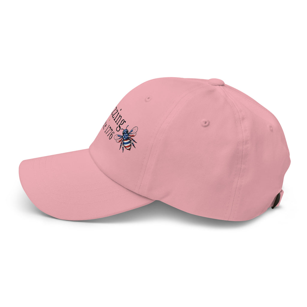 Light pink dad hat with curved brim and embroidered bee graphic on side