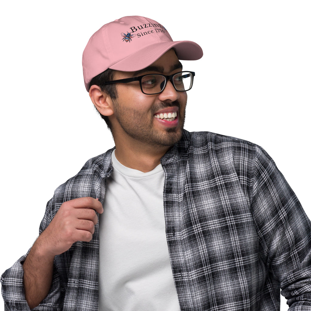Light pink dad hat with curved brim and embroidered bee “Buzzing Since 1776”