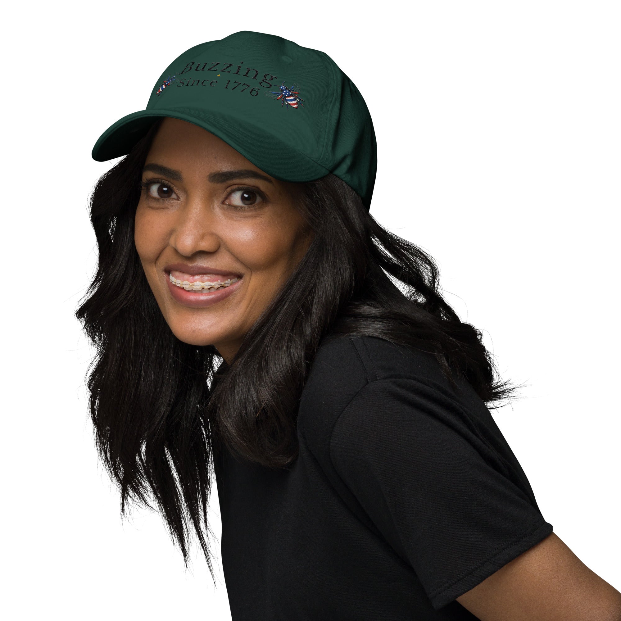 Spruce green dad hat with “Buzzing Since 1776” and bee graphic, worn