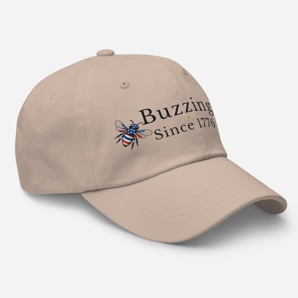 Stone beige dad hat with embroidered bee and “Buzzing Since 1776” text on front