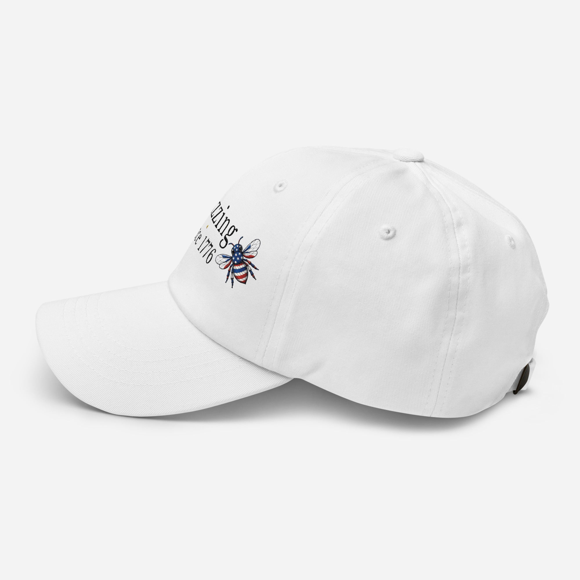 White dad hat with embroidered bee and “Buzzing Since 1776” text on front