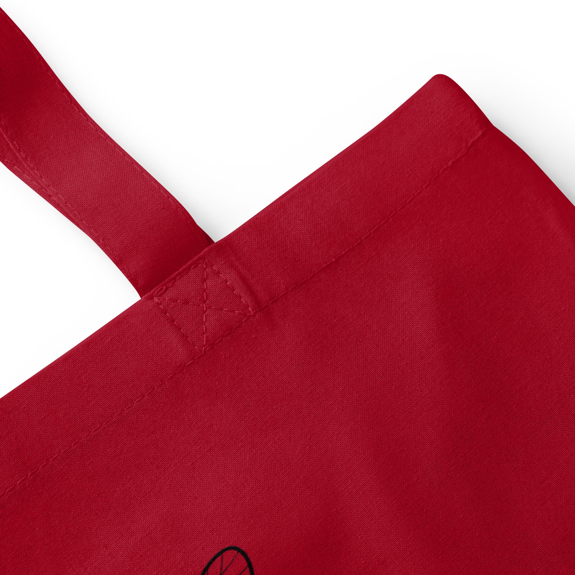 Red cotton tote bag close-up of reinforced handle stitching and seam
