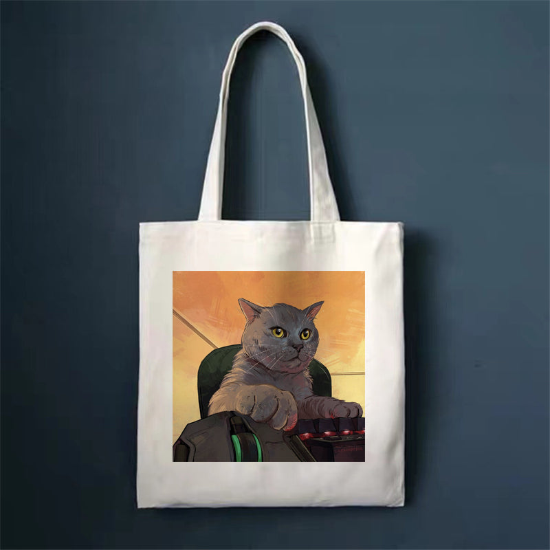 Canvas tote bag with gray cat holding a device illustration on front panel.