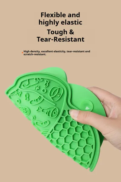 Green silicone lick mat with raised patterns, held in a hand.