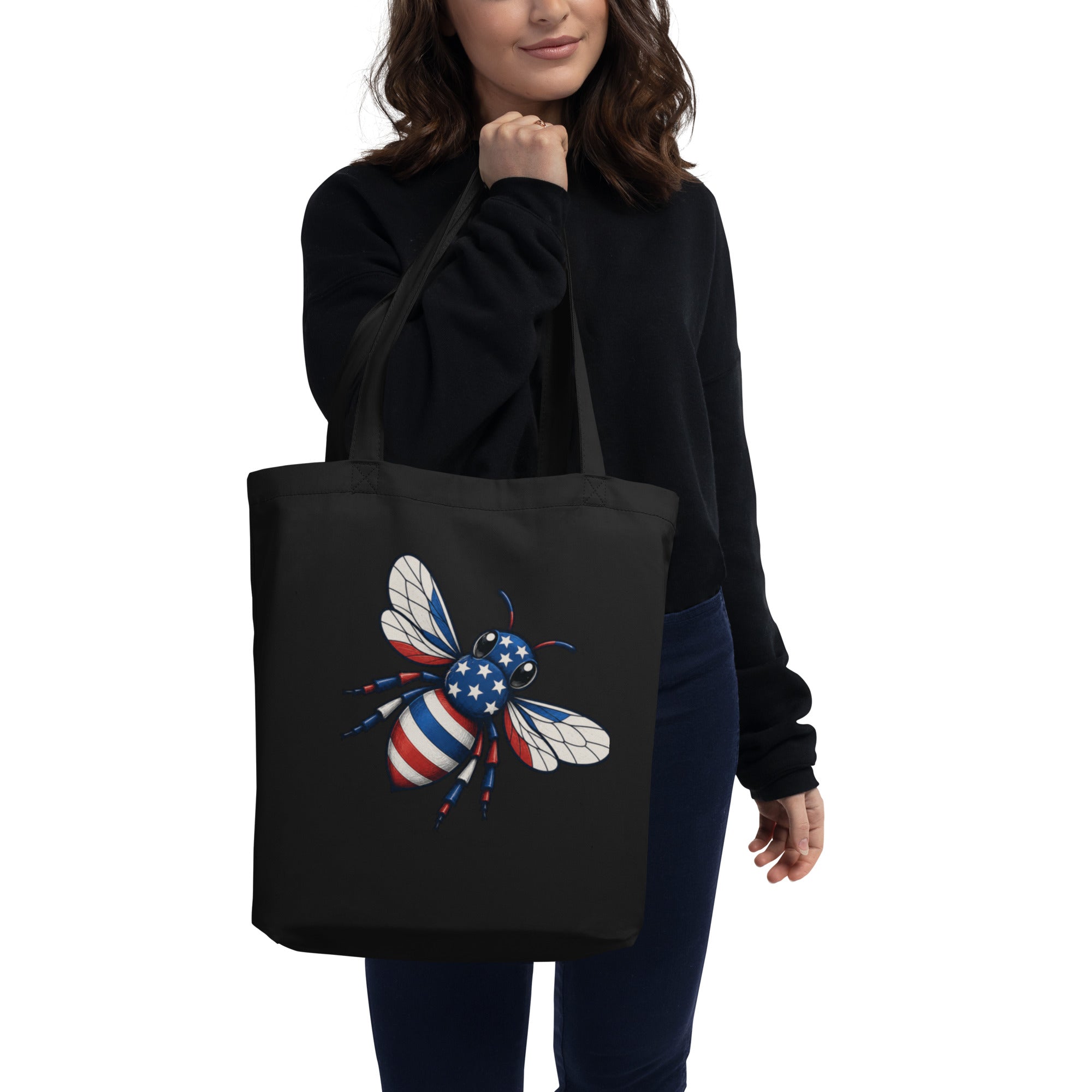Black tote bag being carried, front shows colorful bee graphic with wide handles