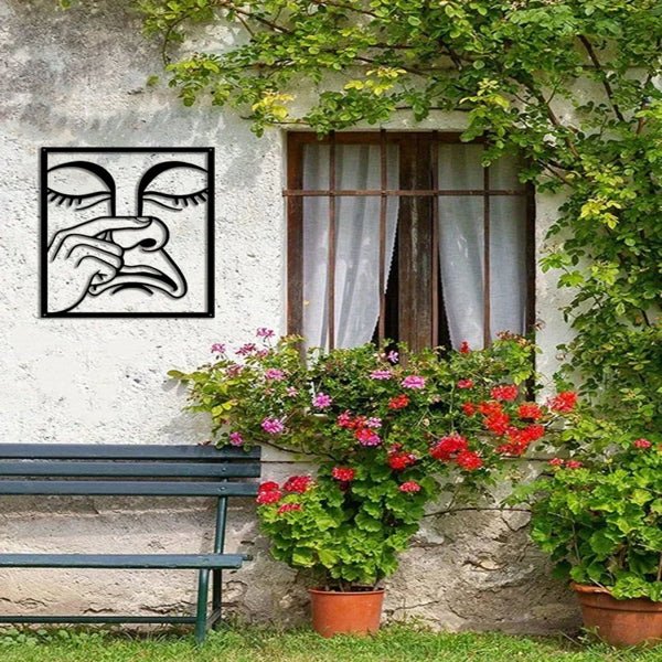 Square metal wall art with black line drawing of a face wiping nose