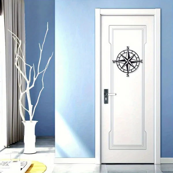 Compass rose metal wall art mounted on a door, black ring with N, E, S, W compass letters