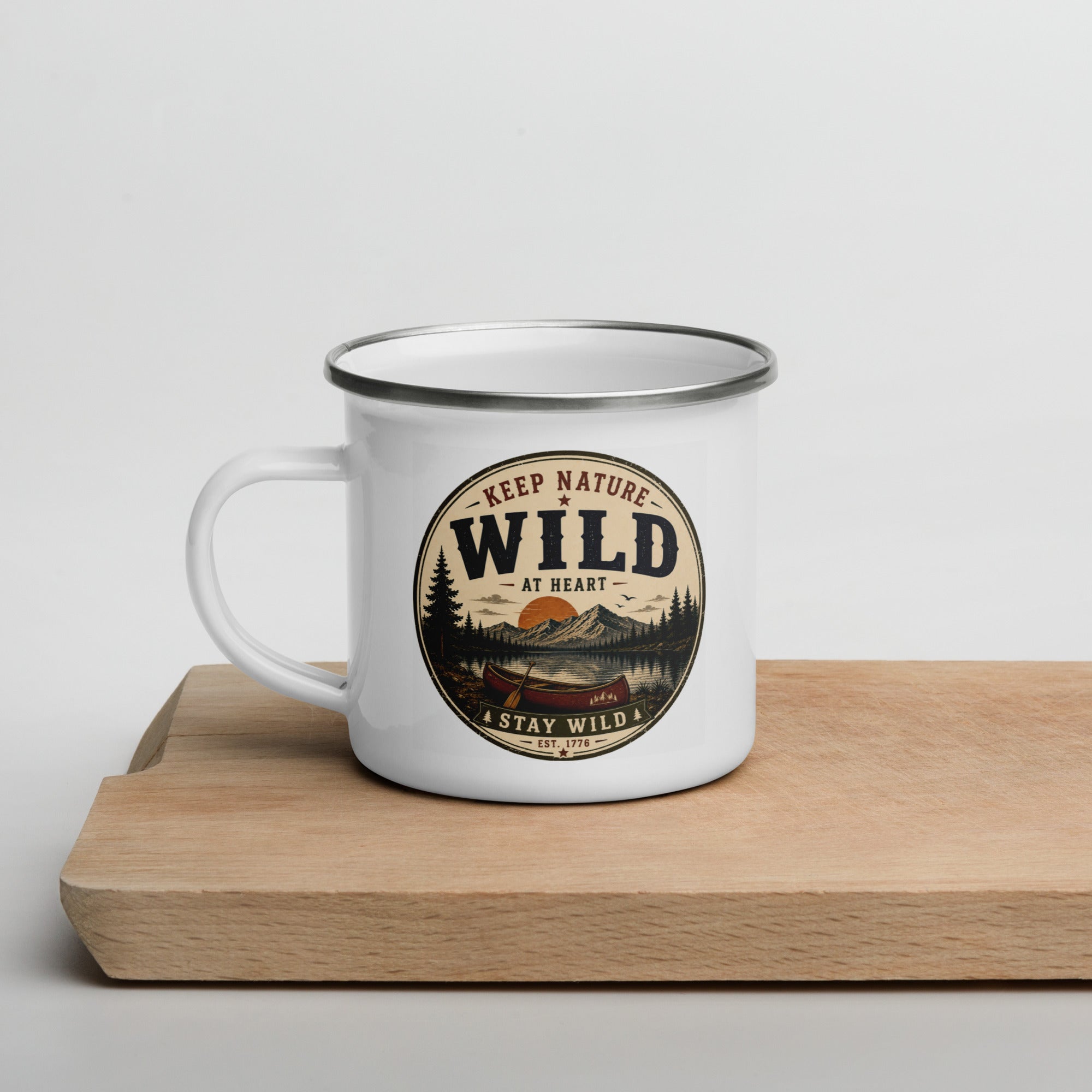 White enamel mug with Wild logo and side handle, gray rim on wooden board
