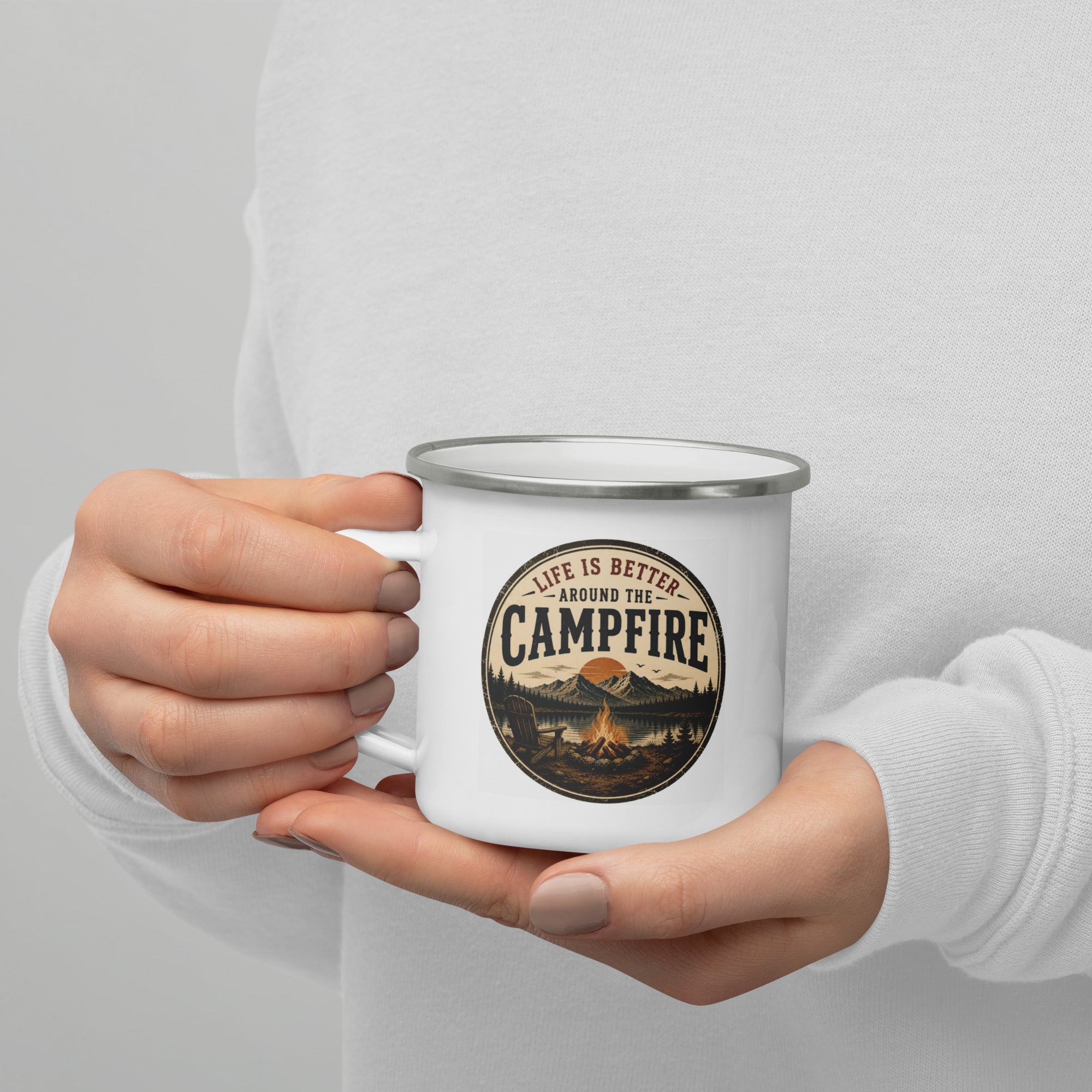 White enamel mug with silver rim, Campfire logo, held in hands