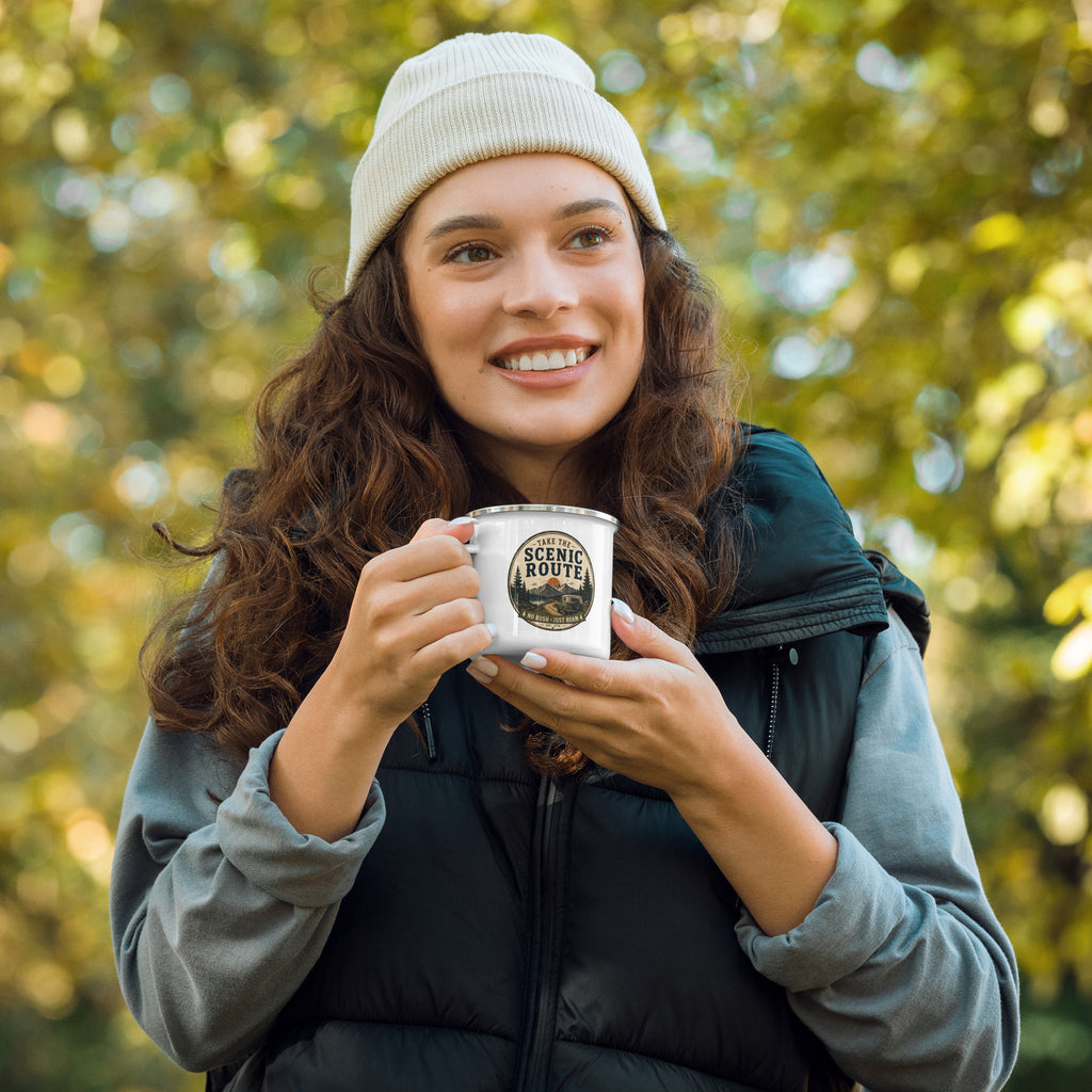 Person holding a white enamel mug with Scenic Route logo and silver rim
