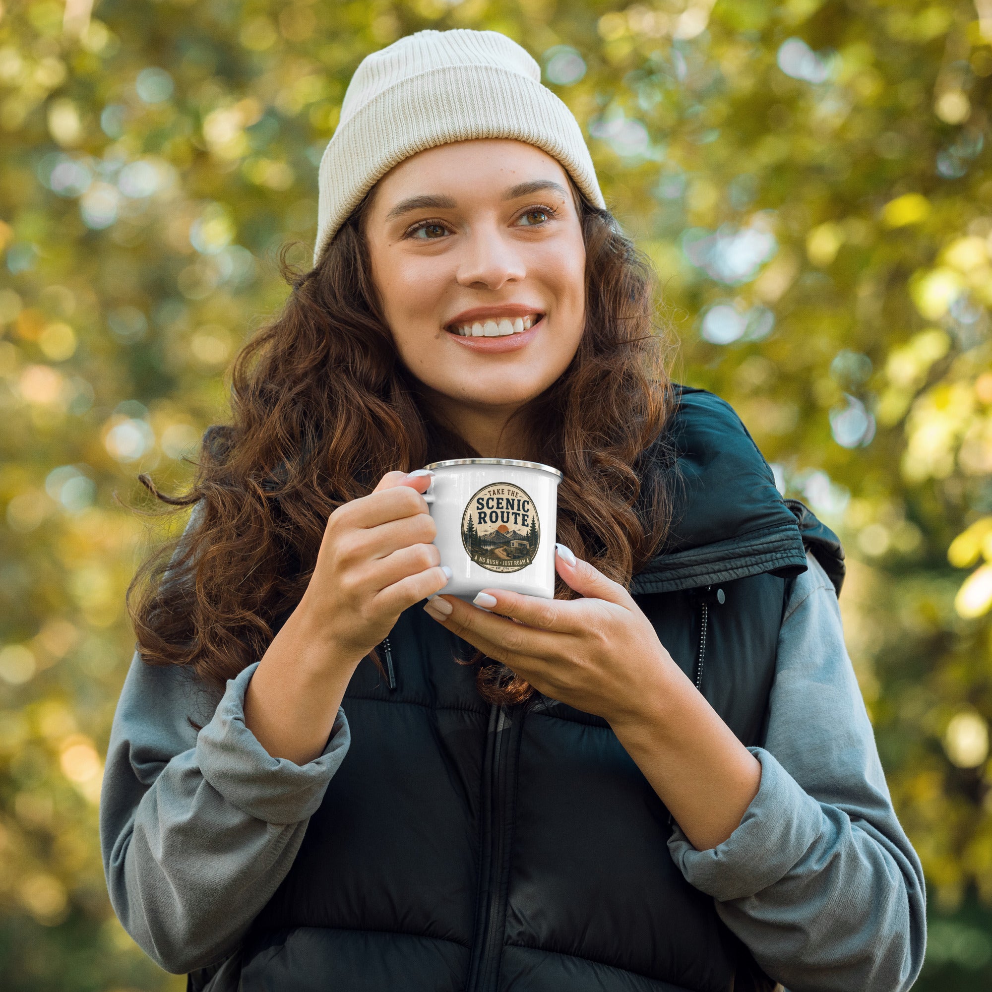 Person holding a white enamel mug with Scenic Route logo and silver rim
