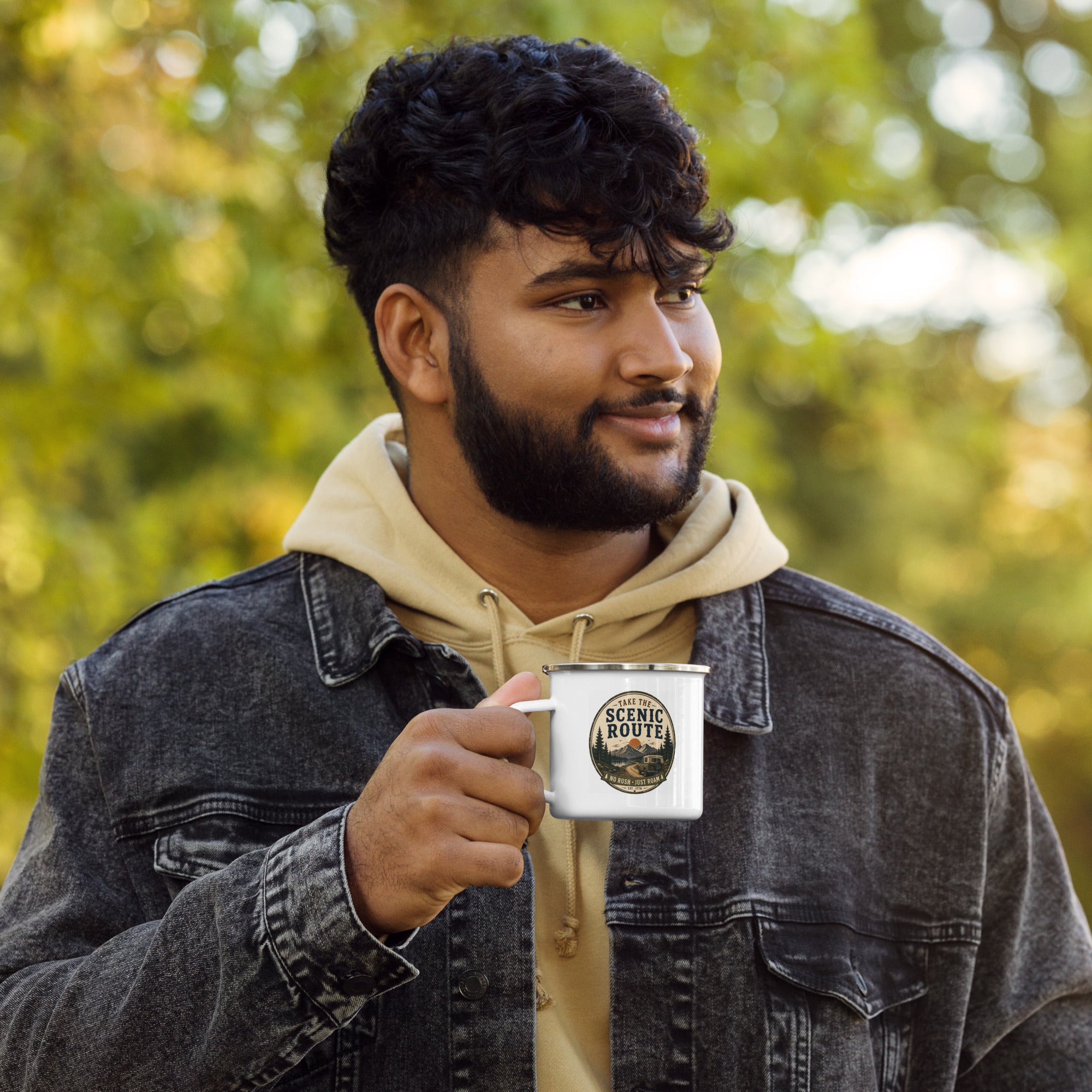Person holding a white enamel mug with Scenic Route logo and silver rim