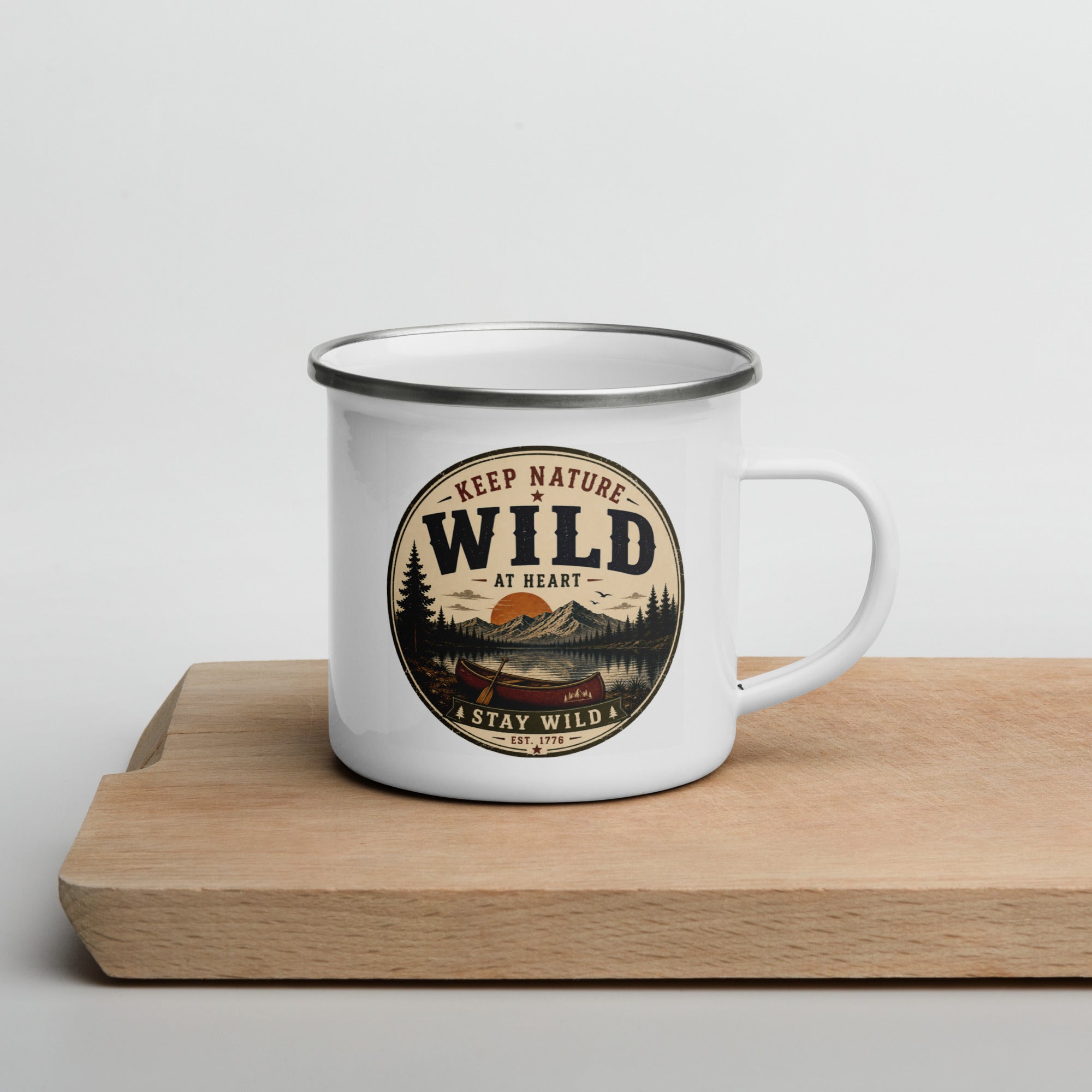 White enamel mug with Wild logo, gray rim and side handle on wooden board
