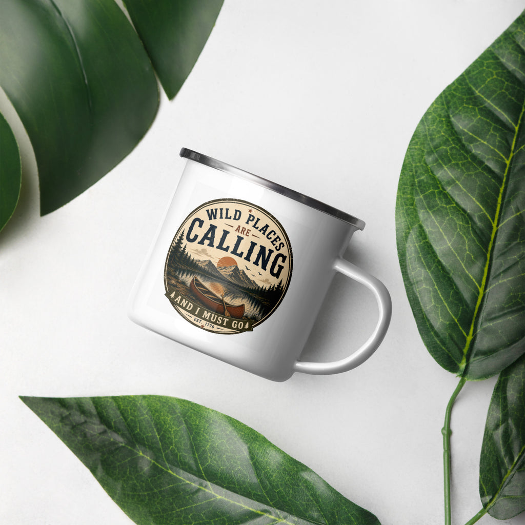 White enamel mug with silver rim, front graphic "WILD PLACES ARE CALLING", tilted view