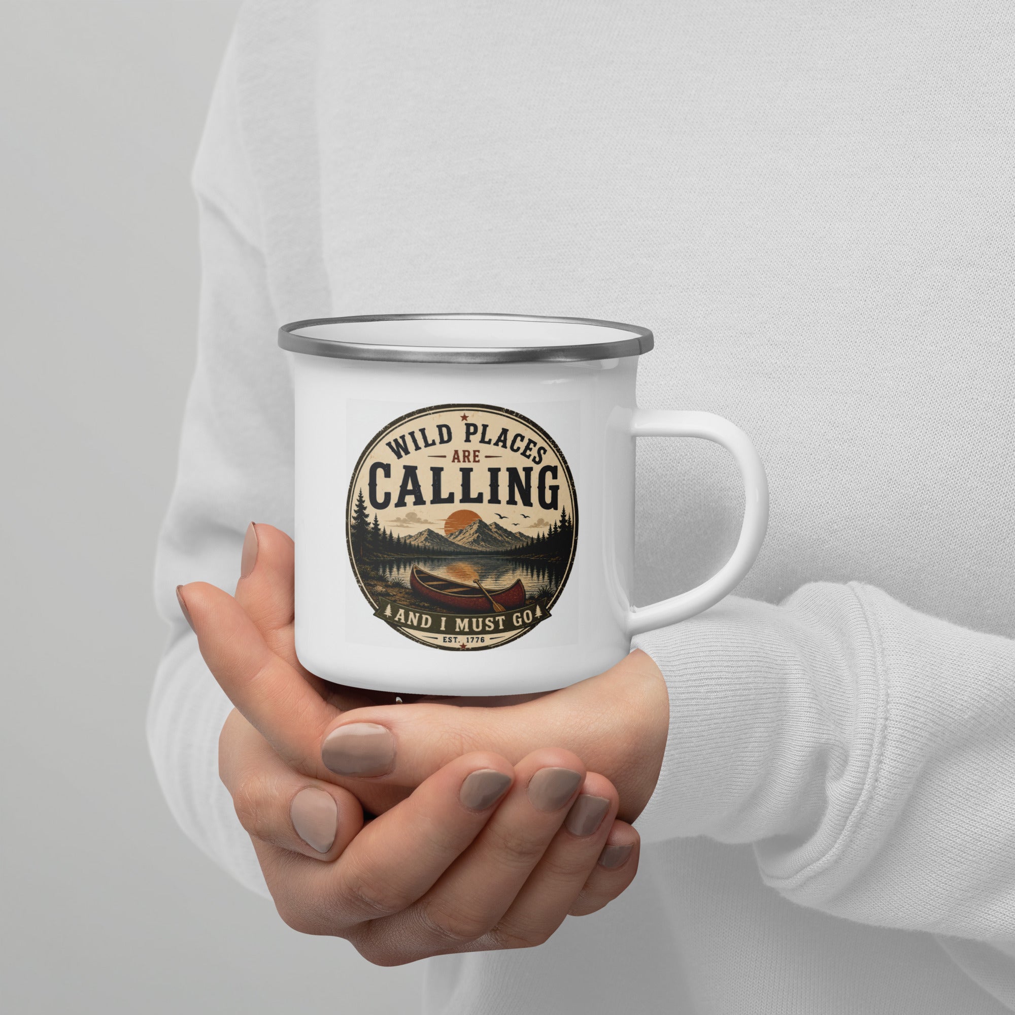 White enamel mug held with both hands, silver rim and calling logo