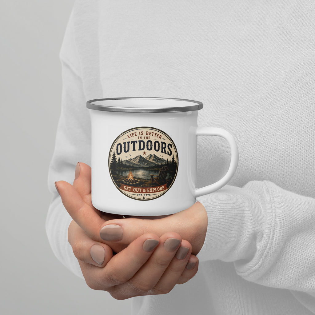 White enamel mug with silver rim held by hands, Outdoors logo on front