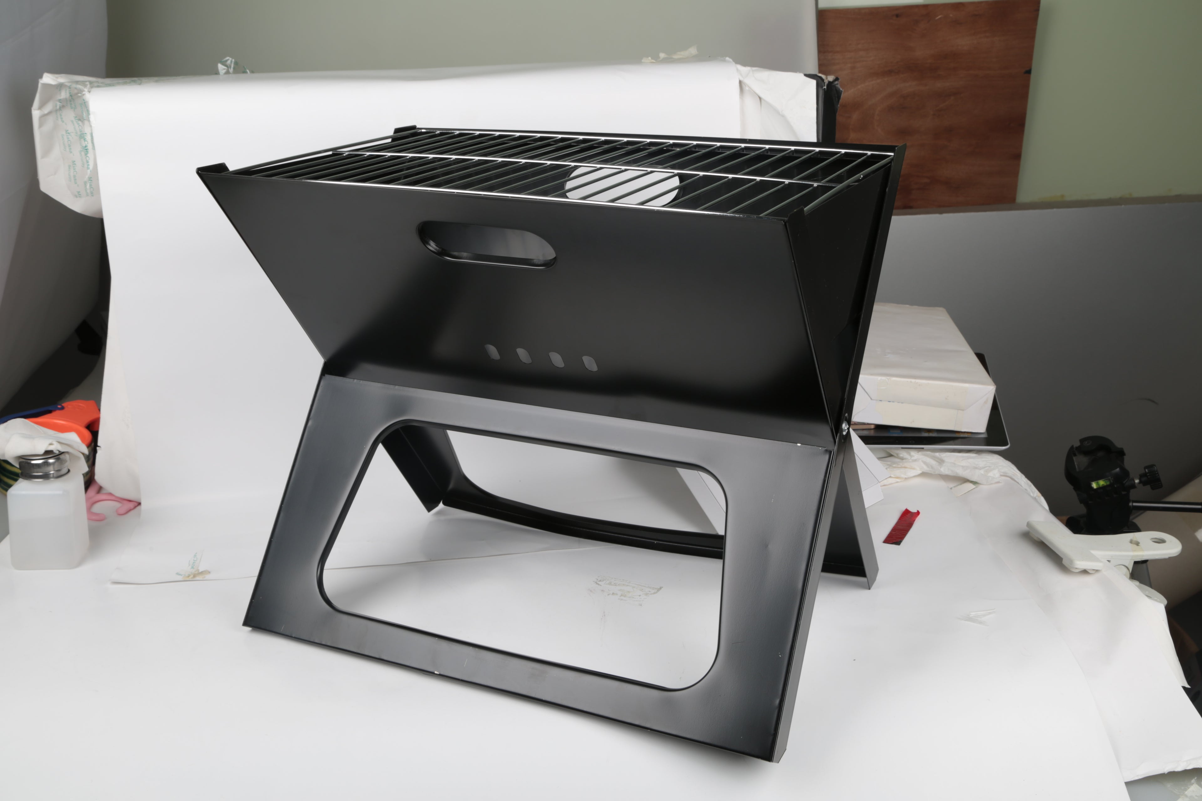 Black charcoal grill with top cooking grate and large front cutout handle frame