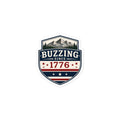 Shield-shaped sticker showing 'BUZZING' and 'SINCE 1776' with mountain scene and stars.