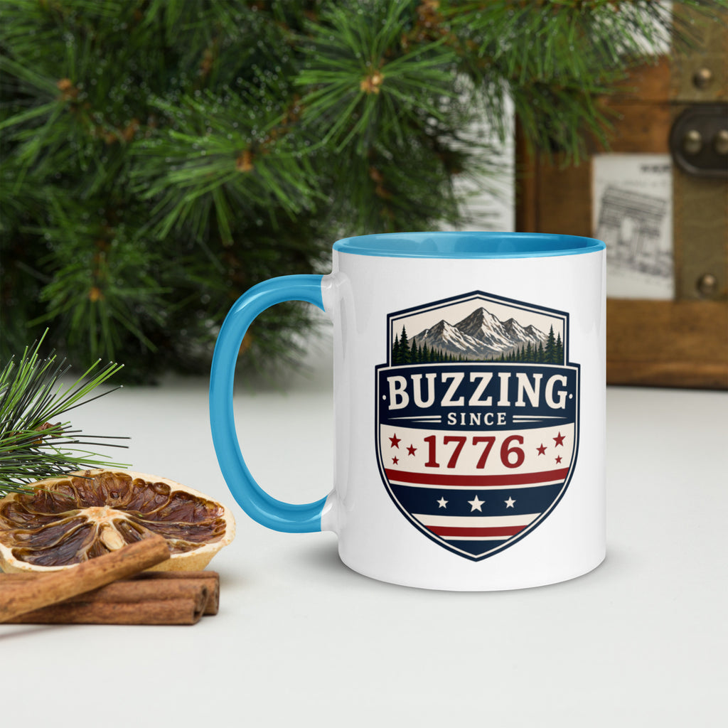 White ceramic mug with blue rim and handle, shield logo reading 'Since 1776'