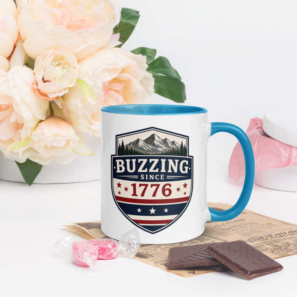 Ceramic mug with “1776” shield graphic, blue rim and handle, white body.