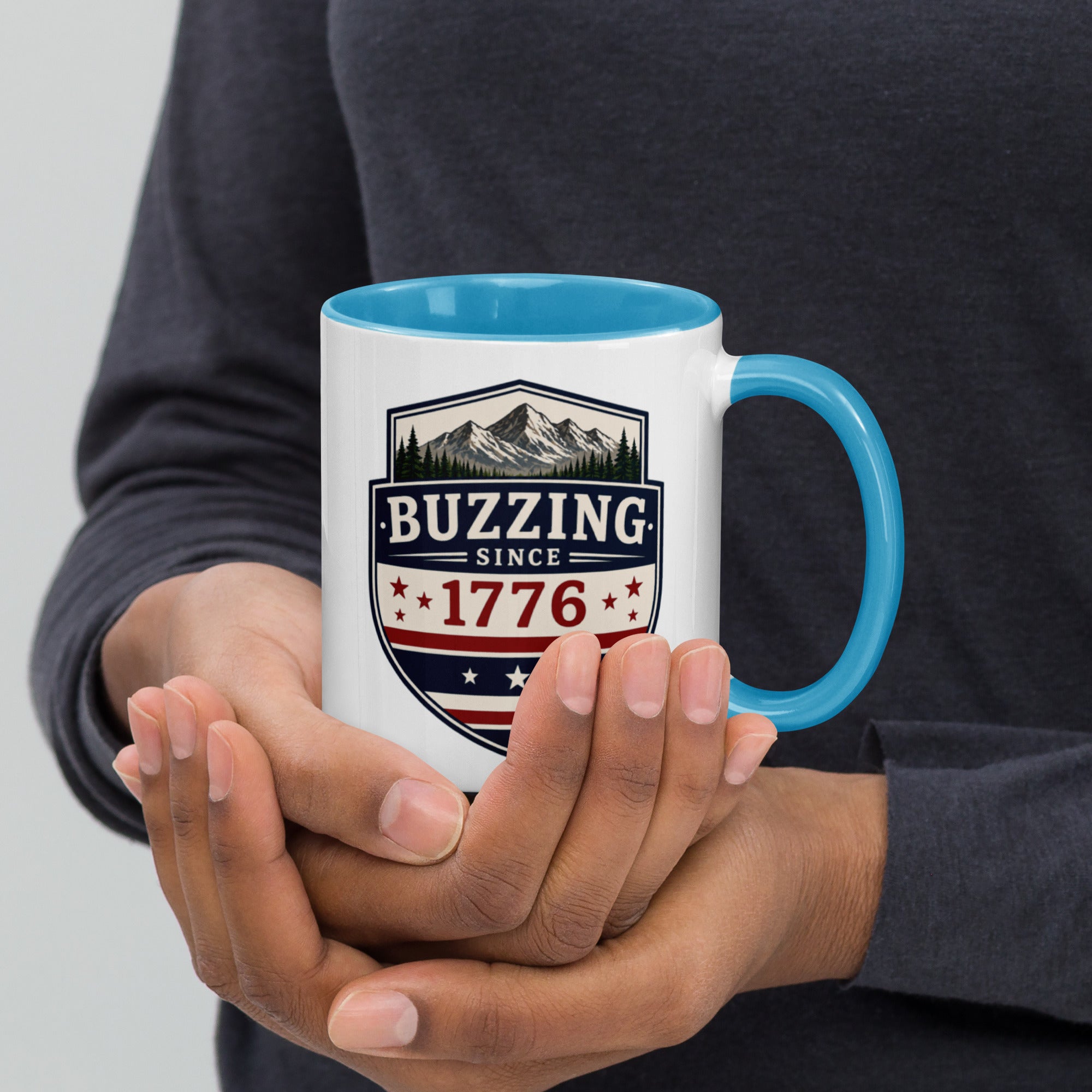 White mug with “Buzzing since 1776” graphic, blue interior and handle.