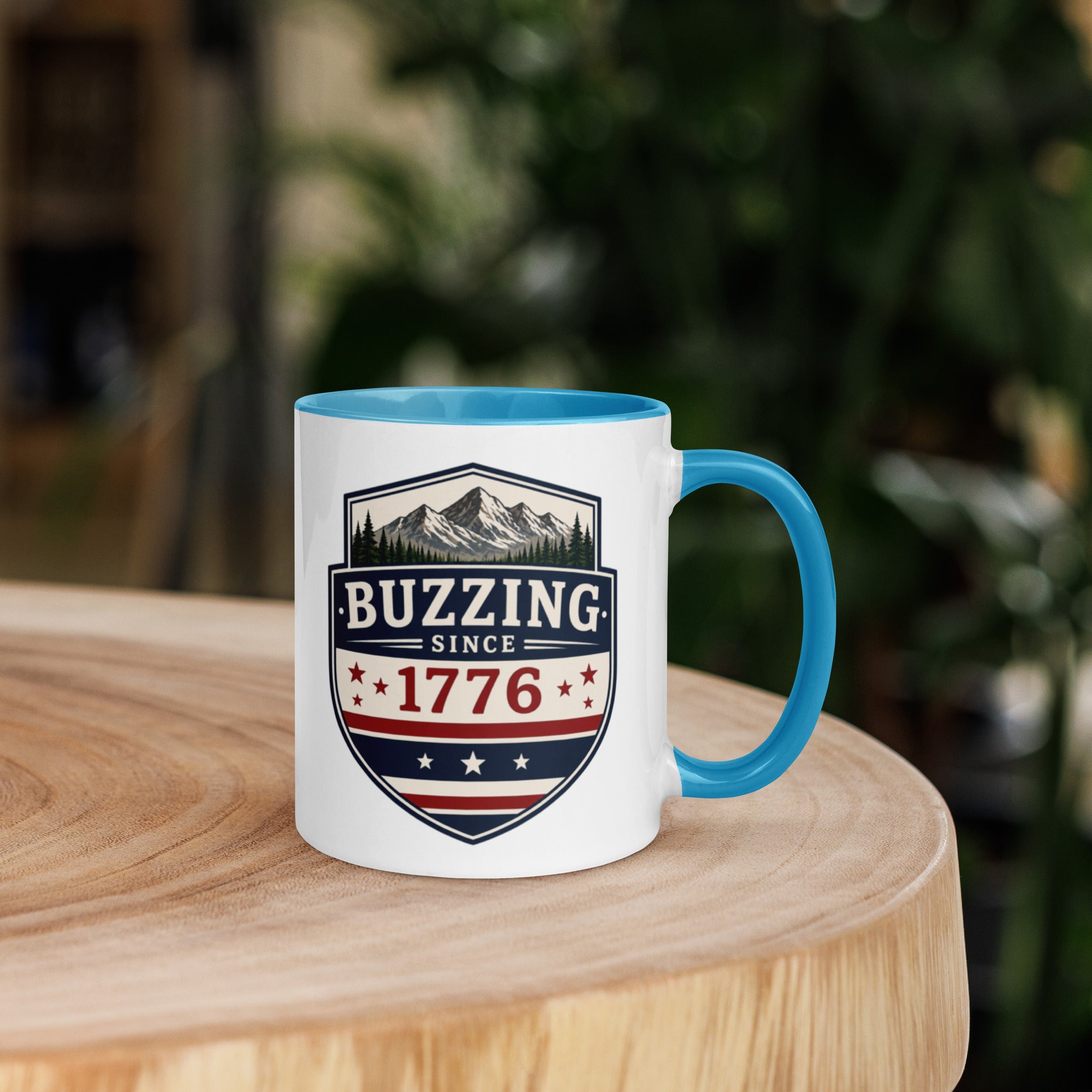 Coffee mug with blue interior rim and handle, white body, “Buzzing Since 1776” graphic