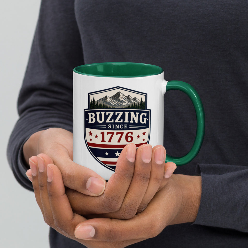 White mug with “Buzzing since 1776” graphic, green interior and handle.