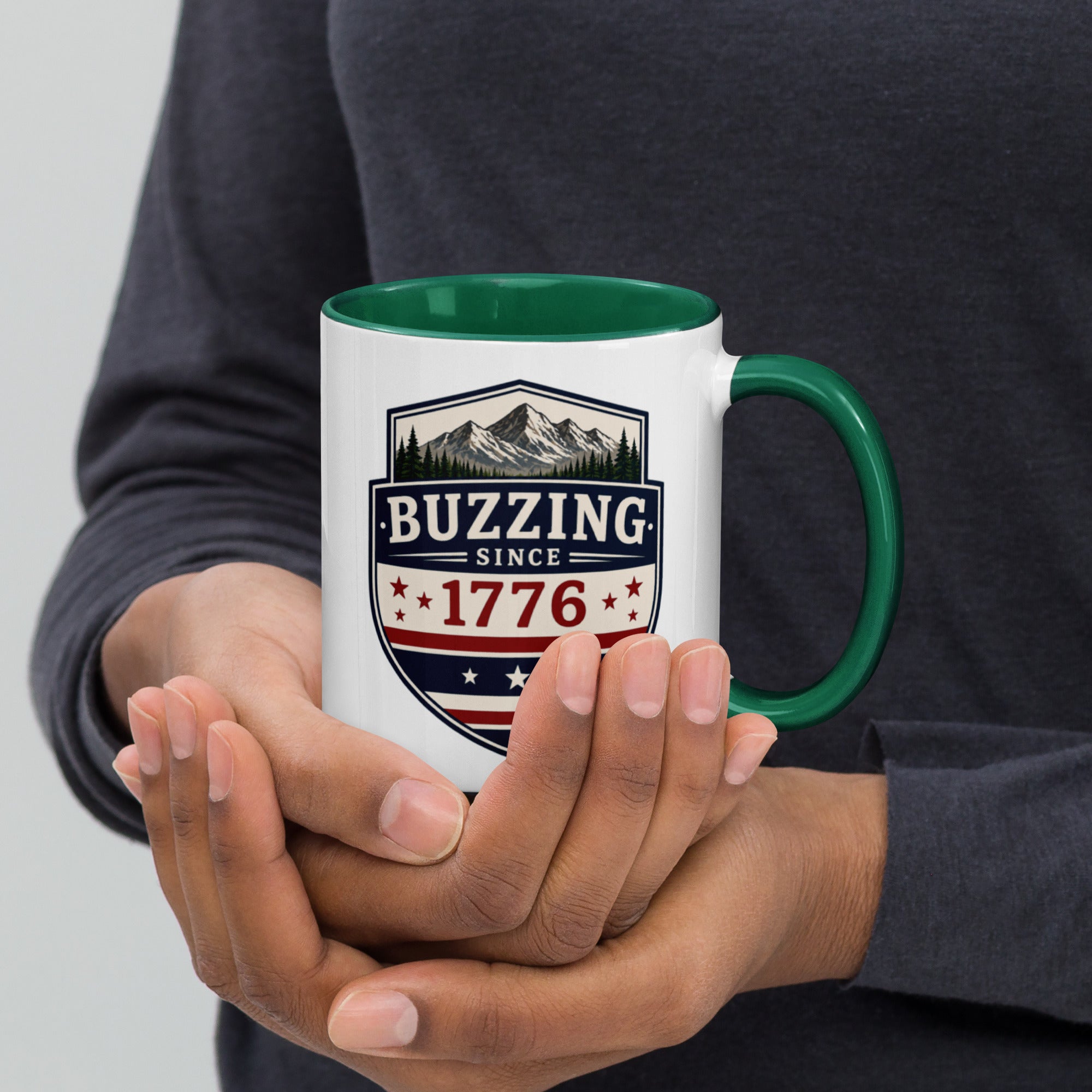 White mug with “Buzzing since 1776” graphic, green interior and handle.