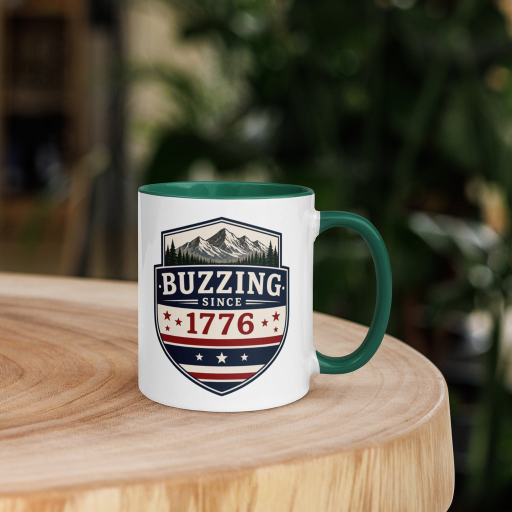 Coffee mug with dark green interior rim and handle, white body, “Buzzing Since 1776” graphic