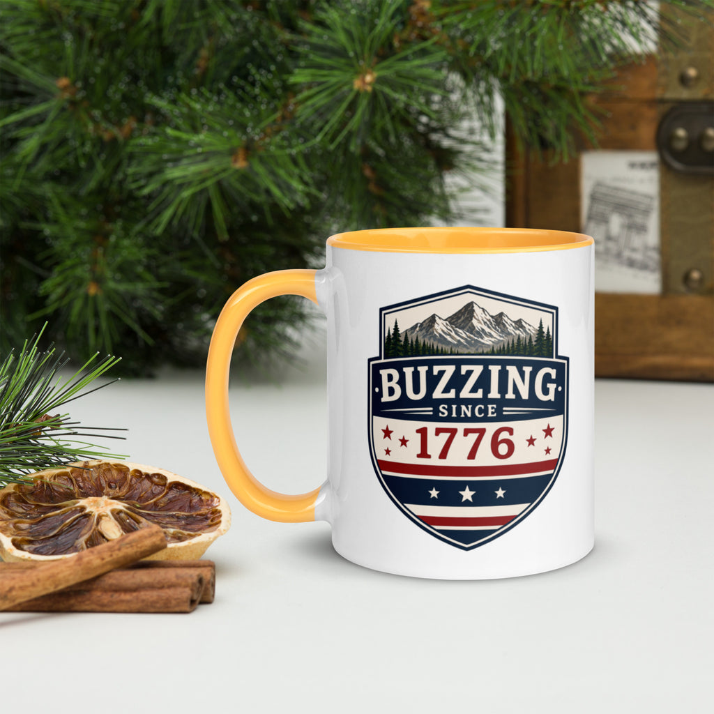 White ceramic mug with golden yellow rim and handle, shield logo reading 'Since 1776'