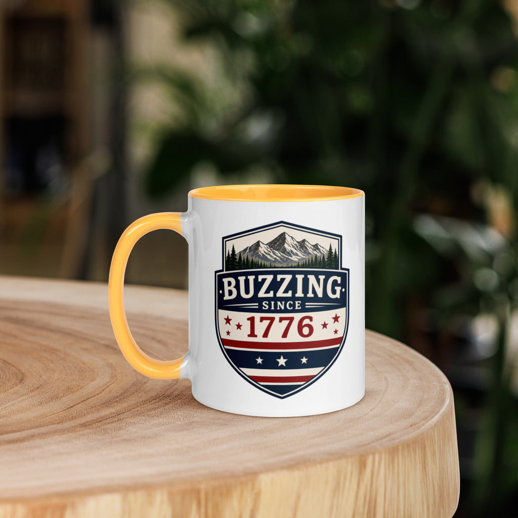 Mug with 'Buzzing Since 1776' crest, white body with golden yellow handle and rim