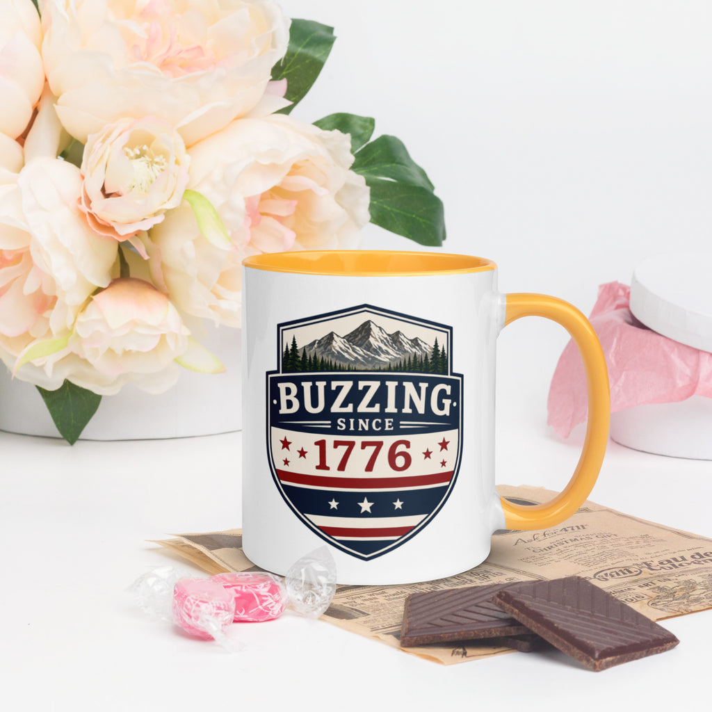 Ceramic mug with “1776” shield graphic, golden yellow rim and handle, white body.
