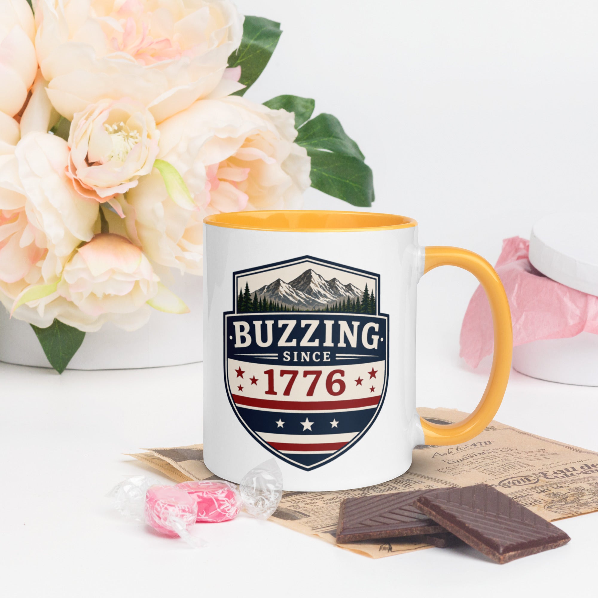 Ceramic mug with “1776” shield graphic, golden yellow rim and handle, white body.