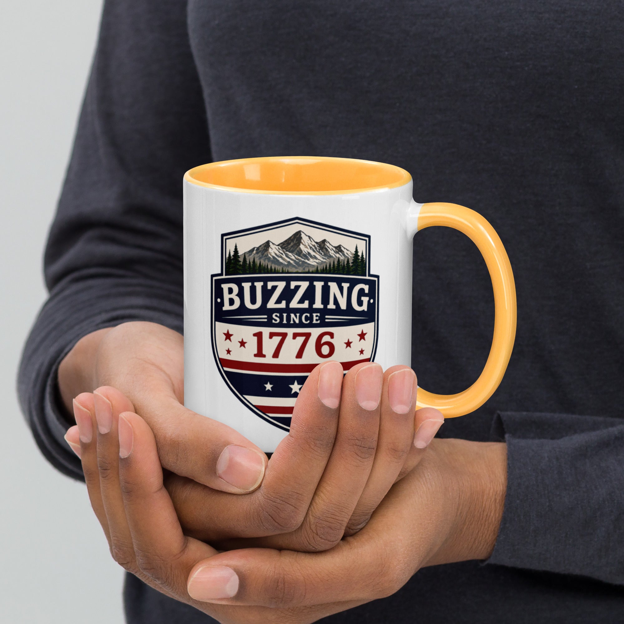 White mug with “Buzzing since 1776” graphic, golden yellow interior and handle.
