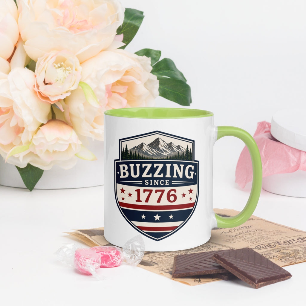 Ceramic mug with “1776” shield graphic, green rim and handle, white body.