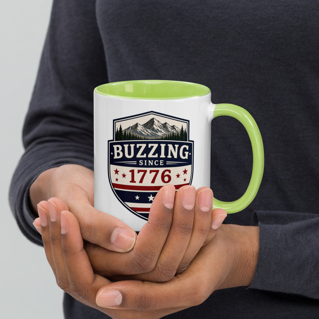 White mug with “Buzzing since 1776” graphic, light green interior and handle.