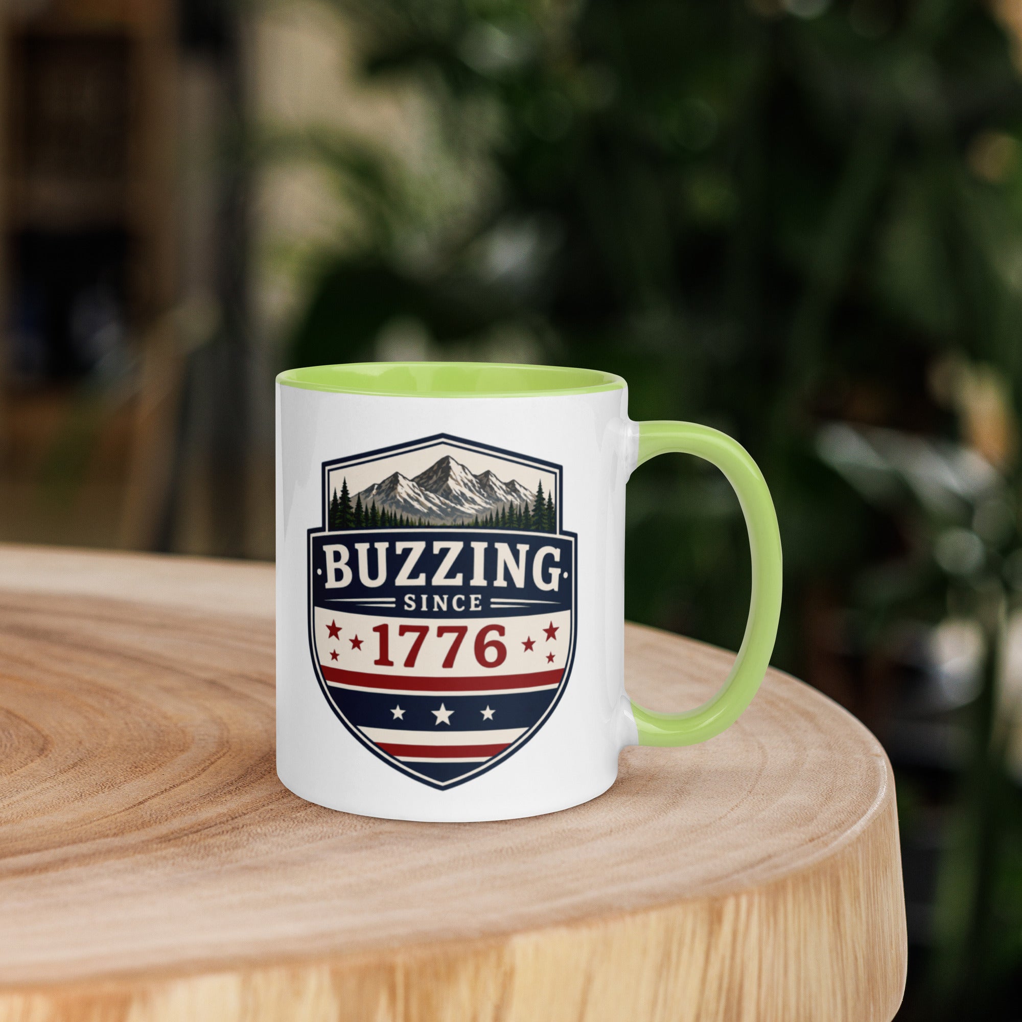 Coffee mug with green interior rim and handle, white body, “Buzzing Since 1776” graphic