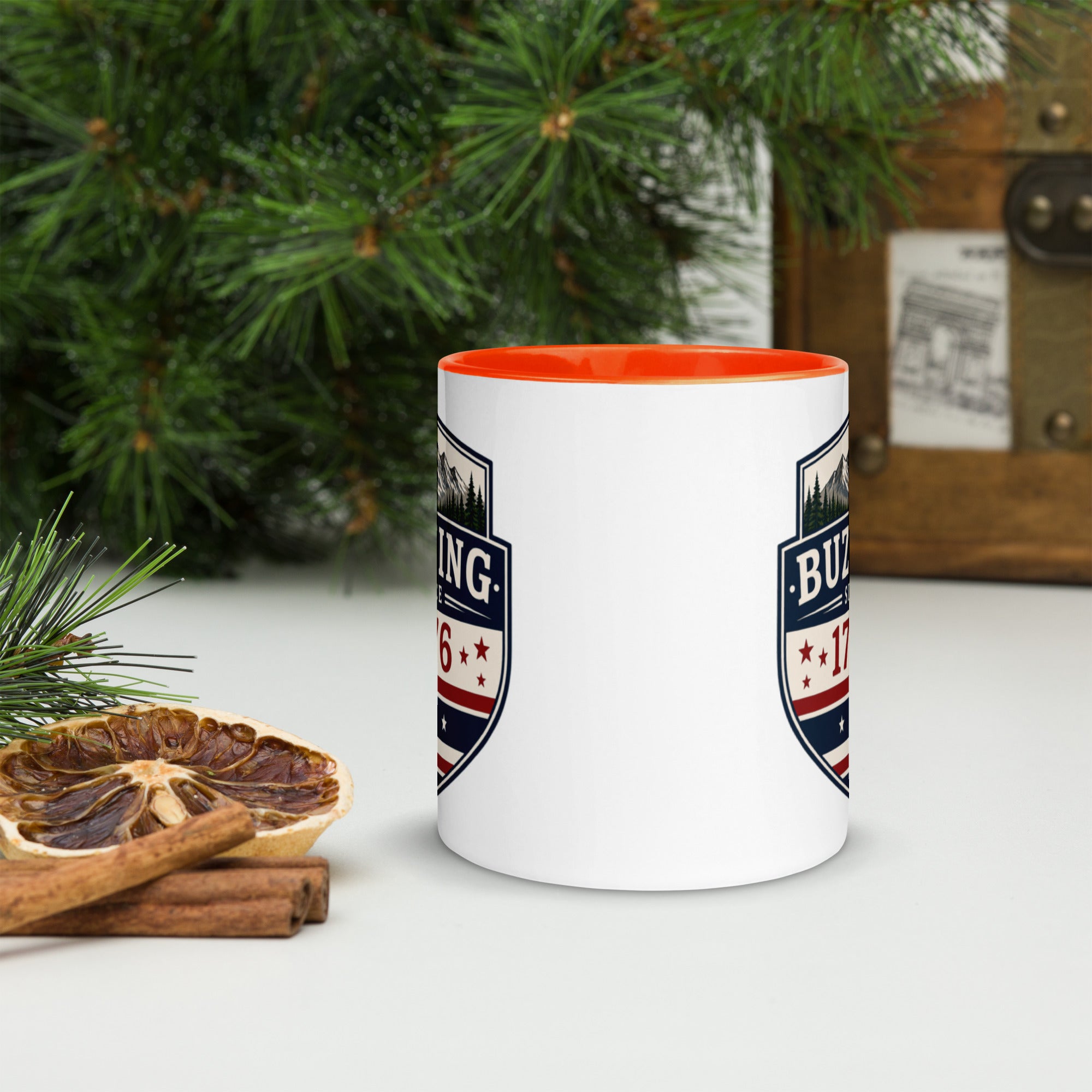 White ceramic mug with printed badge design and orange interior rim
