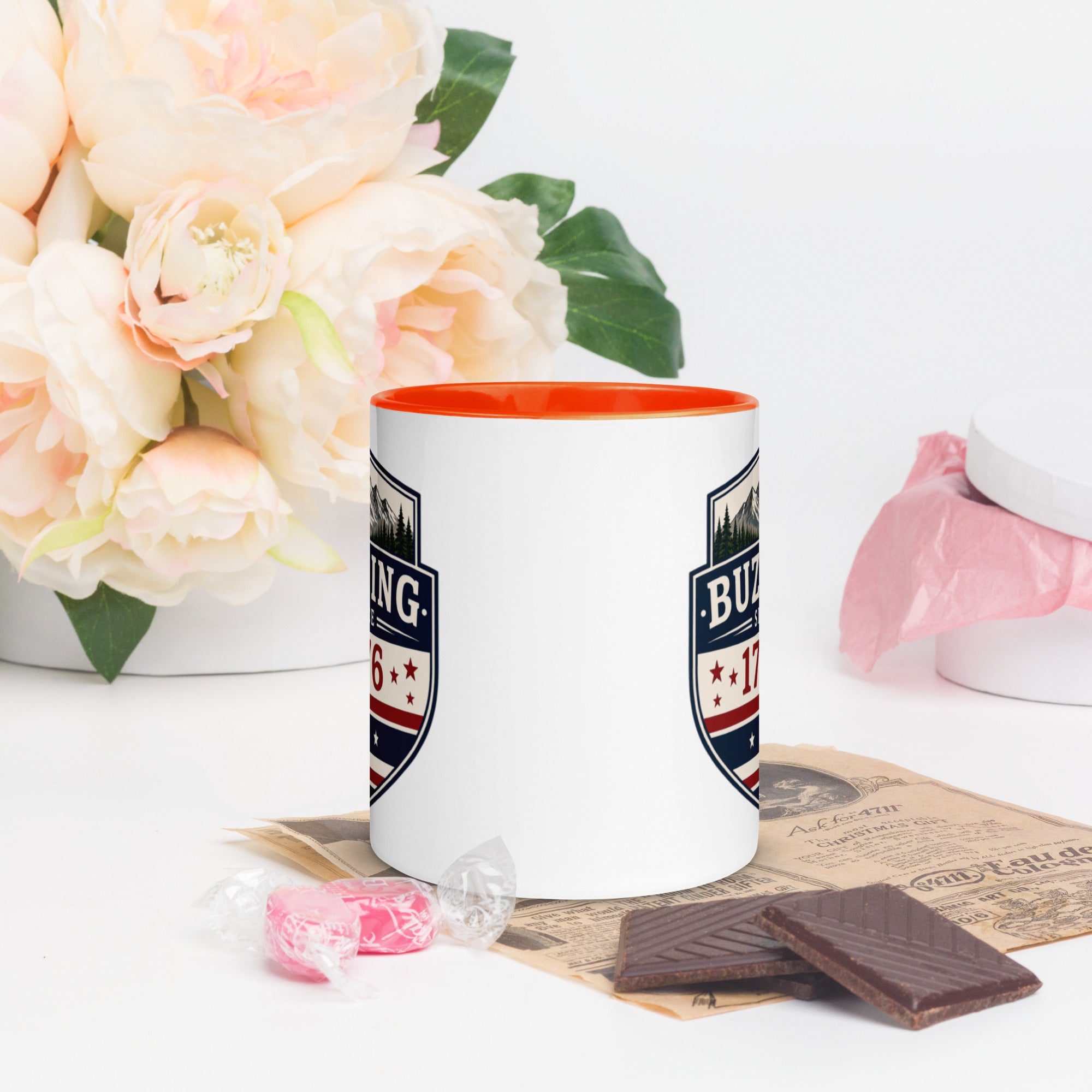 Color-inside ceramic mug with printed shield; orange interior rim.