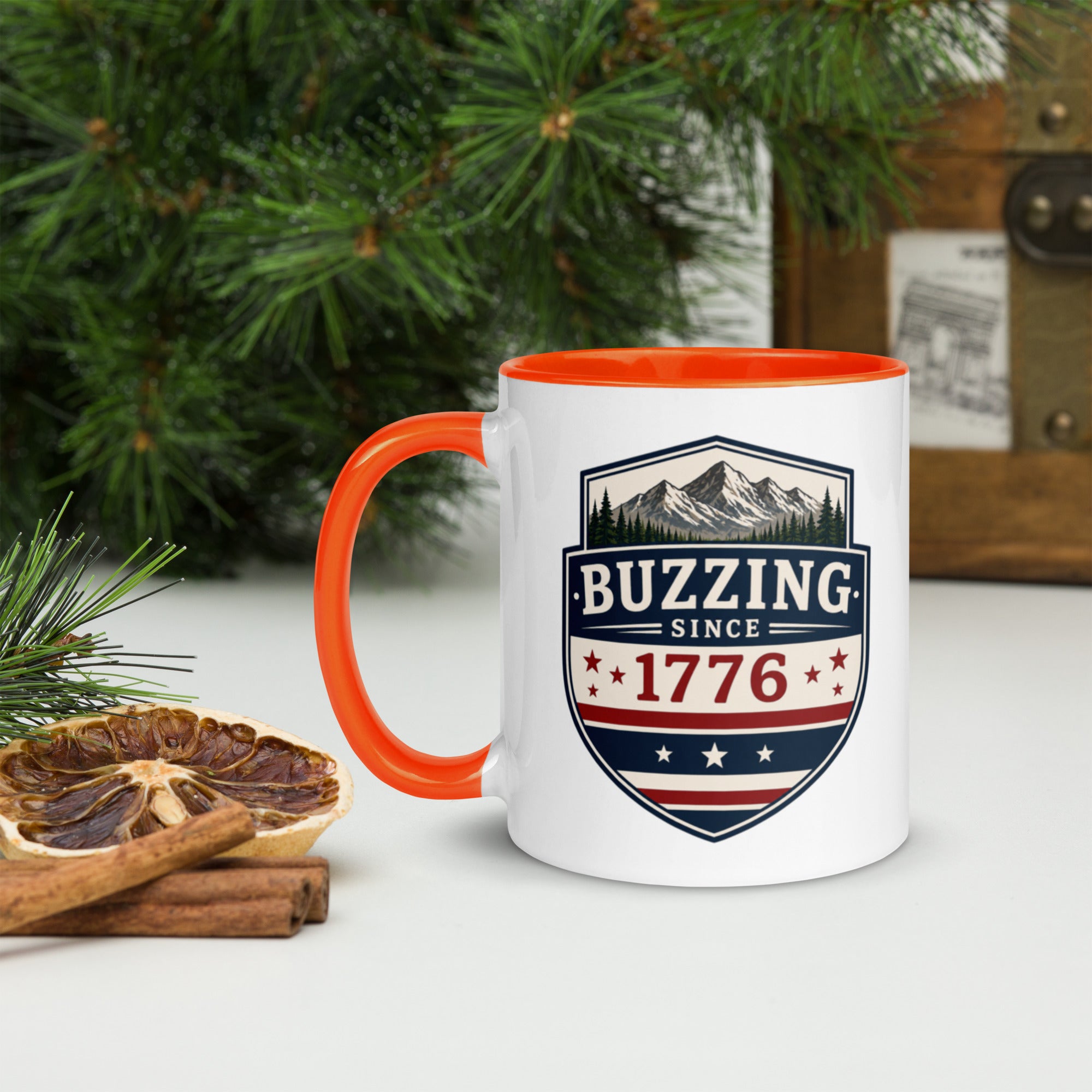 White ceramic mug with orange rim and handle, shield logo reading 'Since 1776'