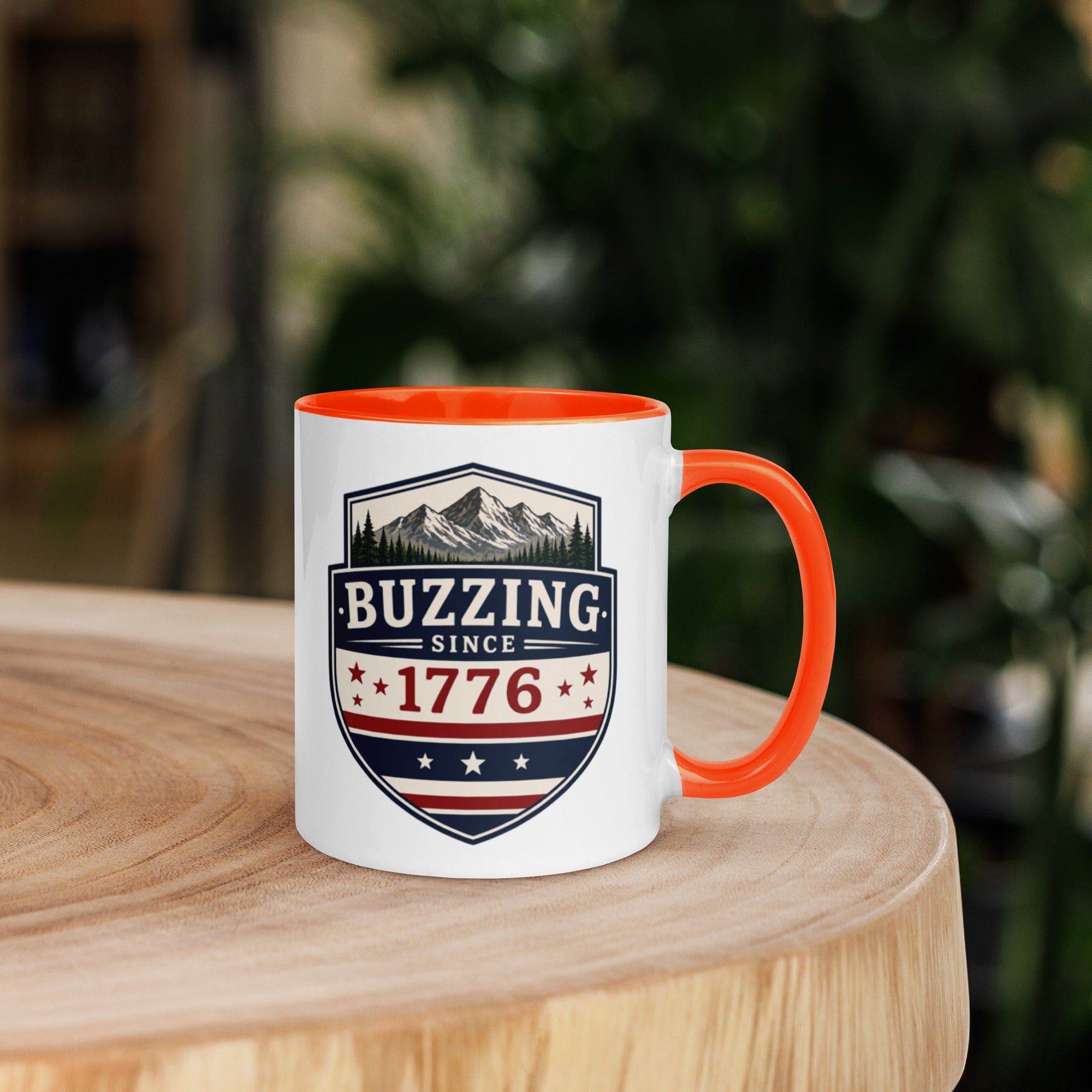 Coffee mug with orange interior rim and handle, white body, “Buzzing Since 1776” graphic