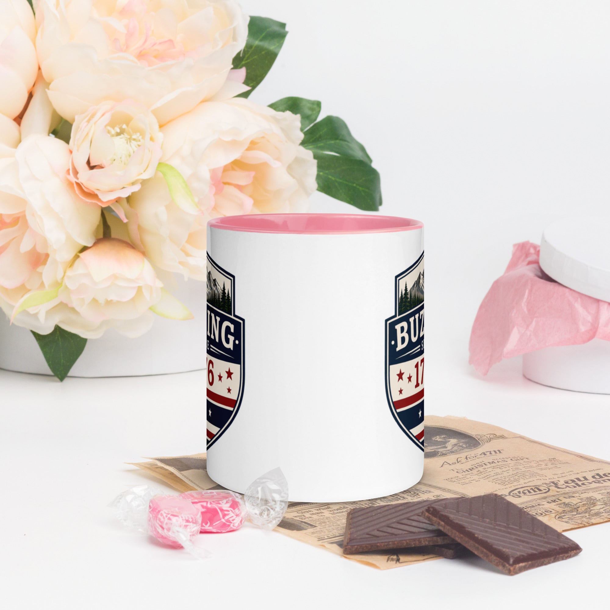 Color-inside ceramic mug with printed shield; pink interior rim.