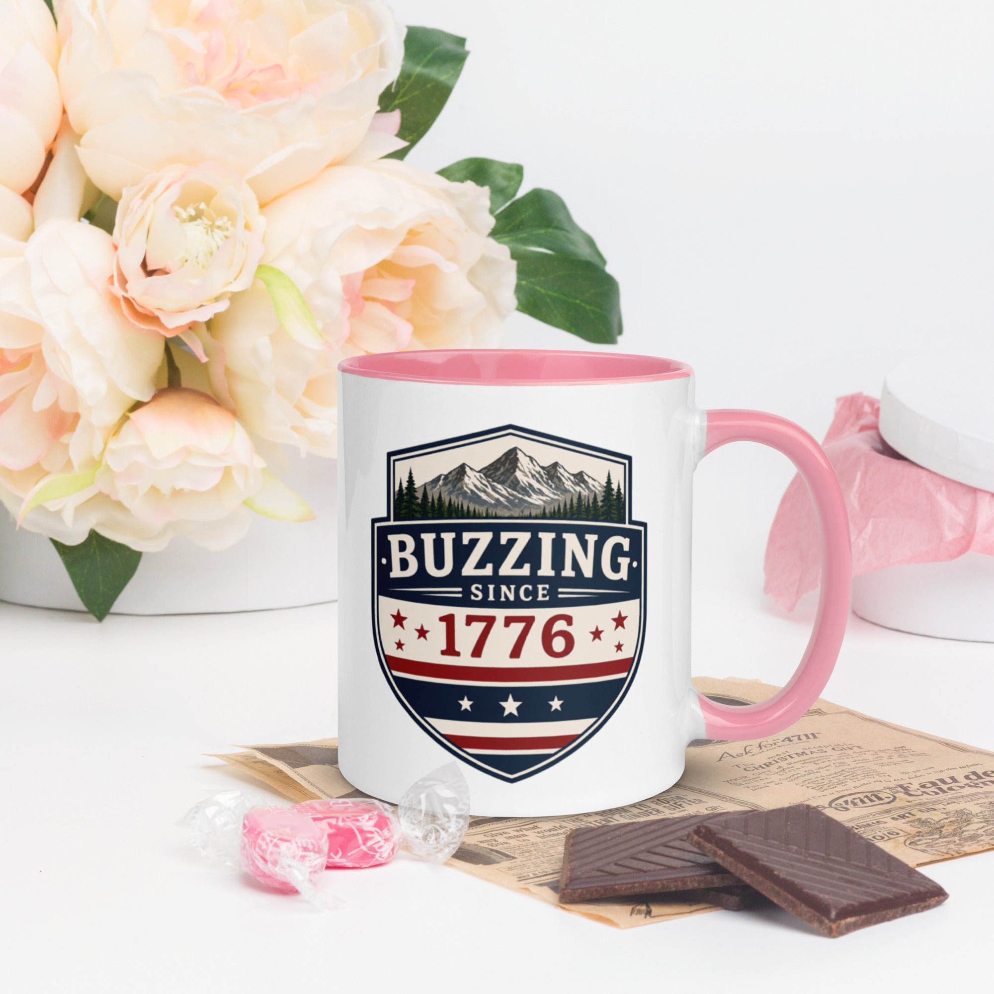Ceramic mug with “1776” shield graphic, pink rim and handle, white body.