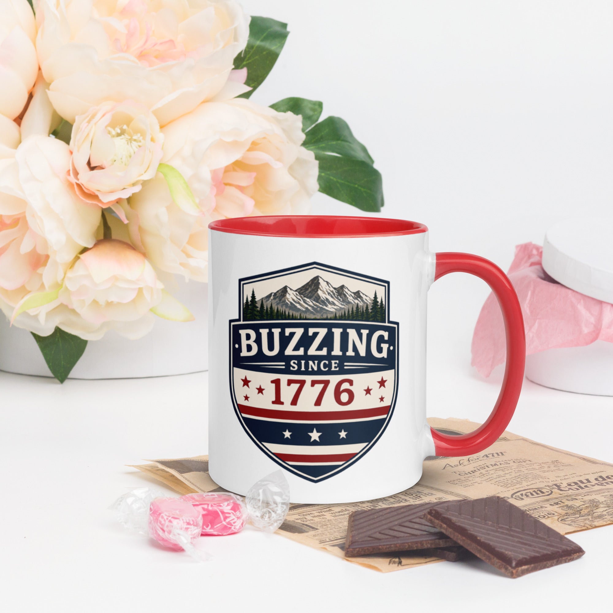 Ceramic mug with “1776” shield graphic, red rim and handle, white body.
