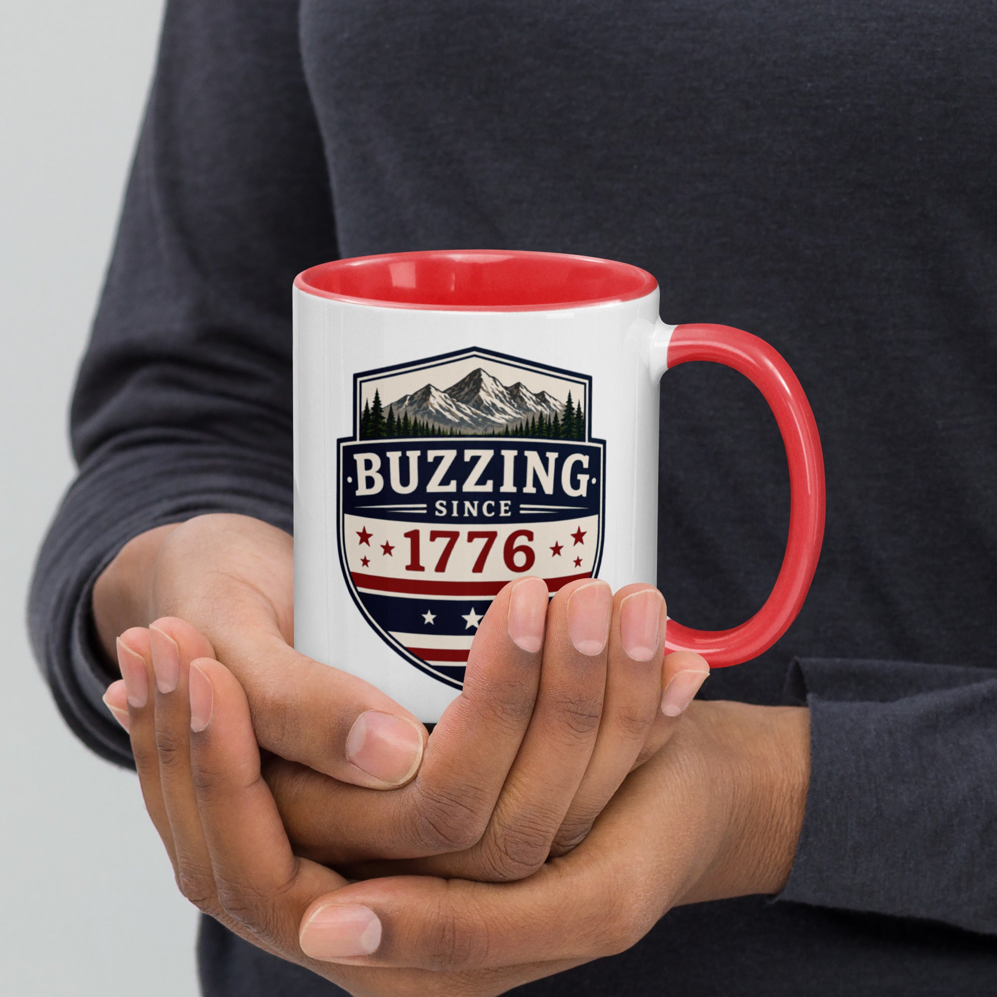 White mug with “Buzzing since 1776” graphic, red interior and handle.