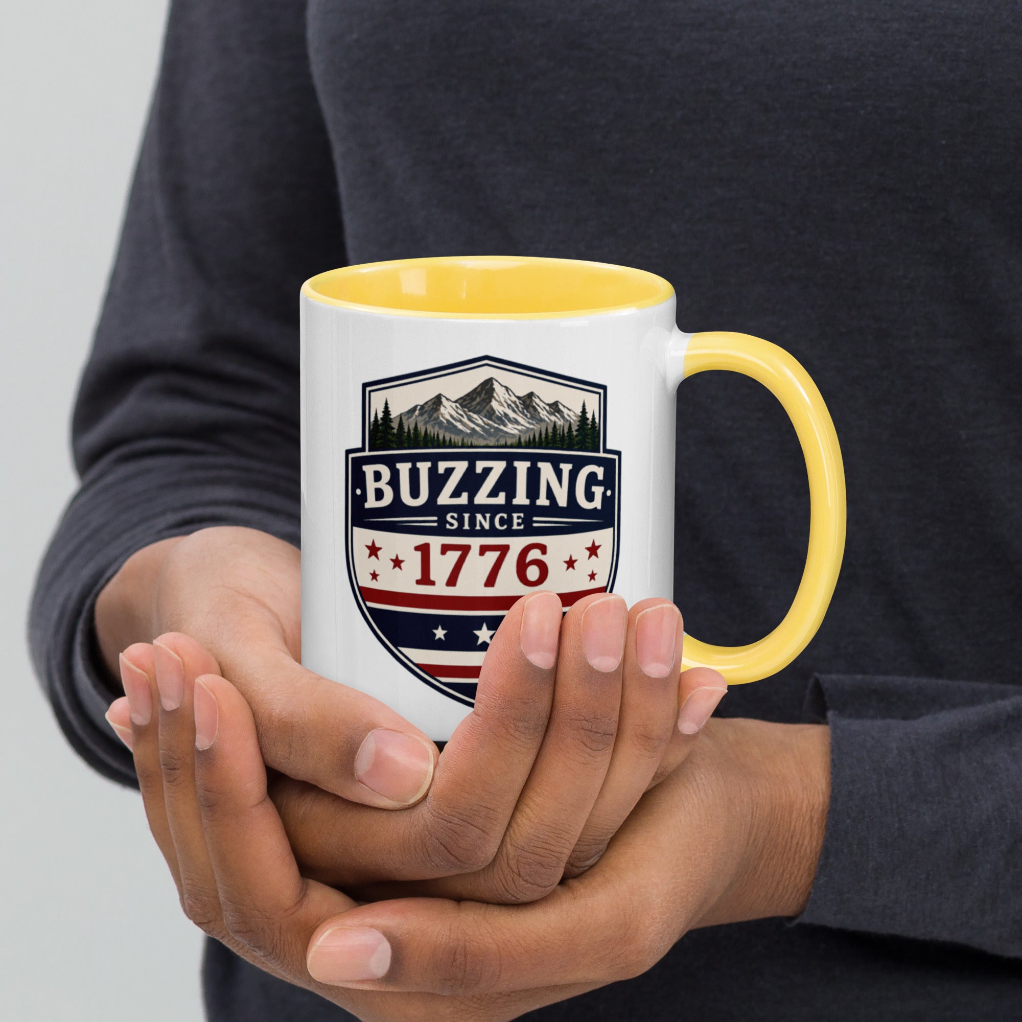 White mug with “Buzzing since 1776” graphic, yellow interior and handle.