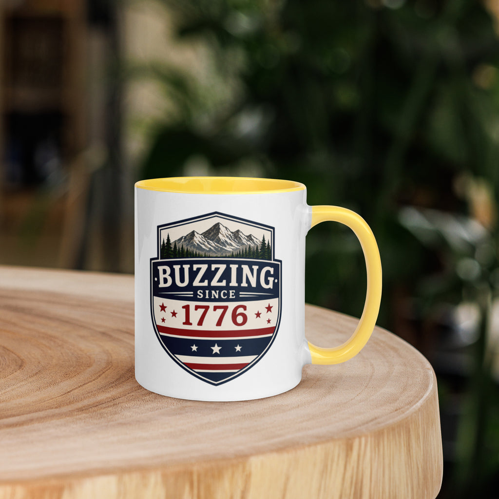 Coffee mug with yellow interior rim and handle, white body, “Buzzing Since 1776” graphic