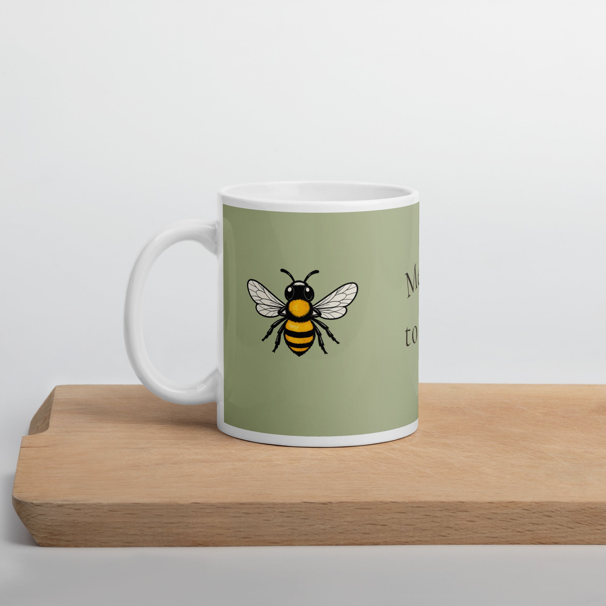 Sage green ceramic coffee mug with bee illustration and white handle