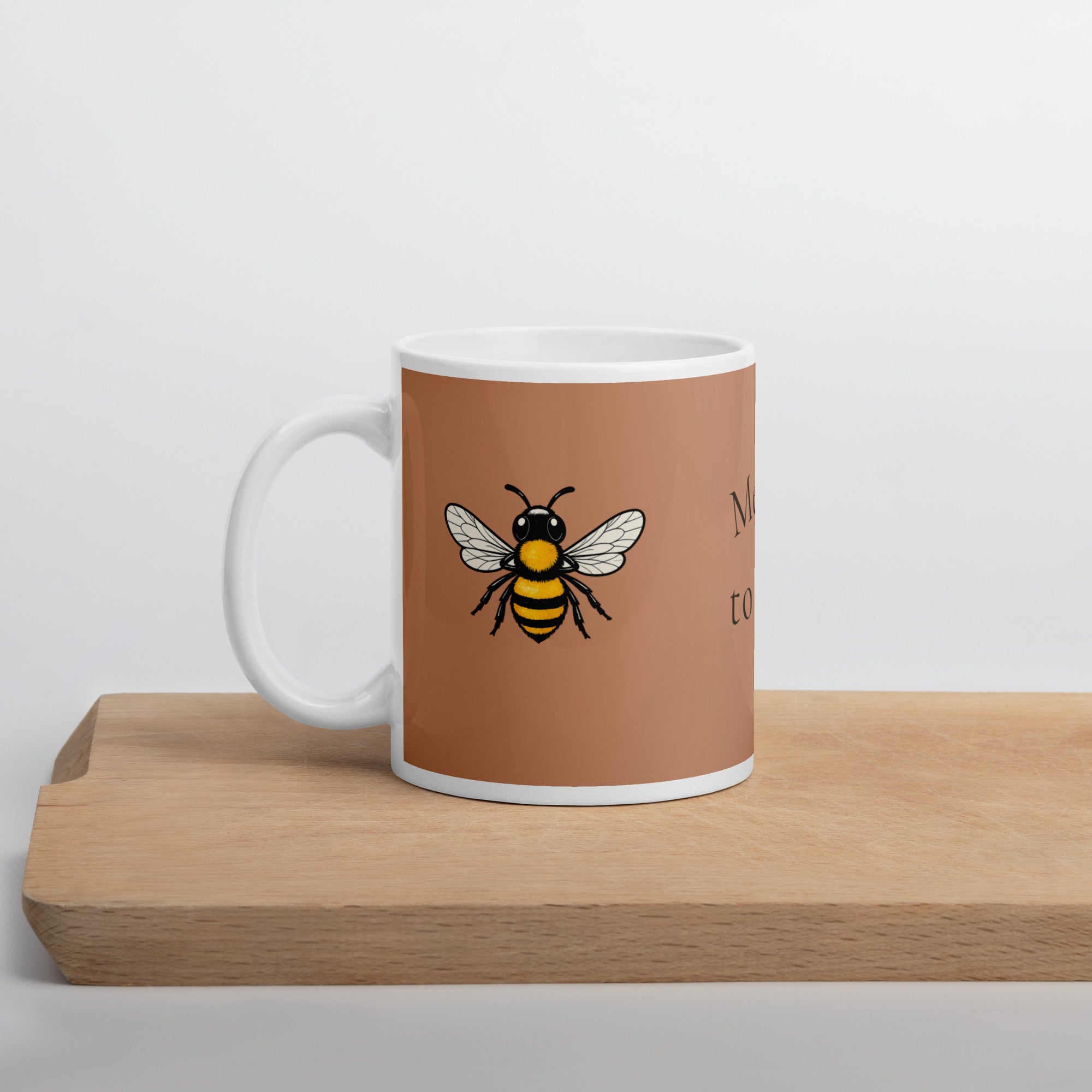 Brown ceramic mug with white handle; bee illustration on front