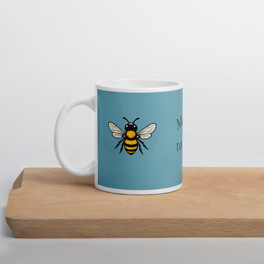 Blue ceramic coffee mug with bee illustration on front, white handle and rim.